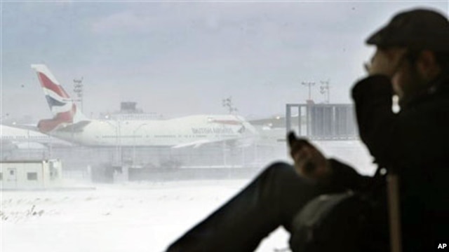 A passenger from San Francisco talks on his phone while a British Airways airplane sits motionless on the runway at John F. Kennedy International Airport in New York, 27 Dec 2010