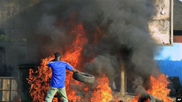 A young man throws a tire onto a fire during a protest by supporters of opposition leader Alassane Ouattara in Abidjan, 03 Dec 2010