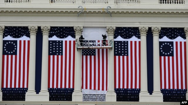 Two workers adjust U.S. flags on the Capitol as preparations continue for the second inauguration of President Barack Obama in Washington, D.C., January 17, 2013. 