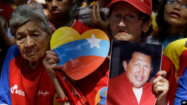 A woman holds a picture of Venezuela's President Hugo Chavez as supporters gather at Simon Bolivar square in Caracas,Venezuela, December  9, 2012.