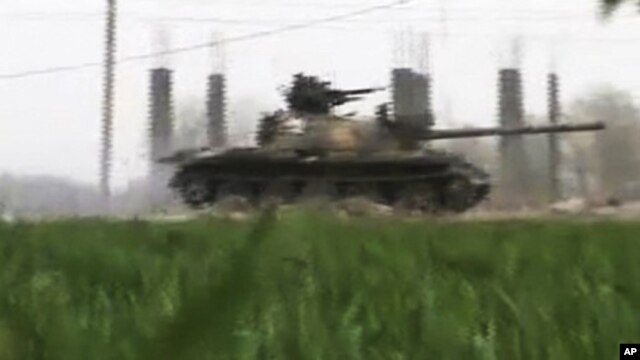 This image made from amateur video and released by Shaam News Network March 26, 2012, purports to show a Syrian military tank in Deir el-Zour, Syria. 