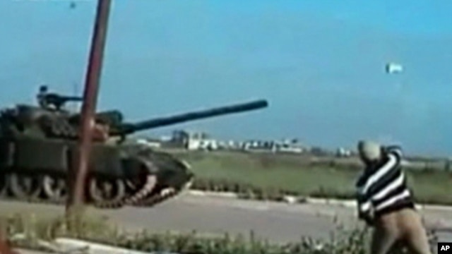 A man throws a rock at a passing tank in a location given as Deraa on April 25, 2011, in this still image from an amateur video