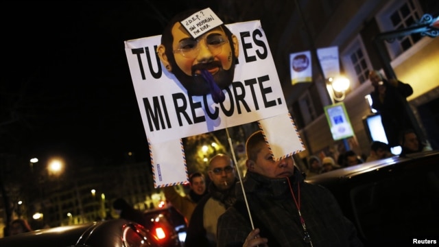 A demonstrator carries a sign with a mask resembling Spanish Prime Minister Mariano Rajoy, as they cut off traffic after a protest outside the headquarters of the ruling People's Party (Partido Popular) in Madrid, February 2, 2013.