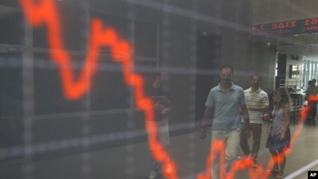 People are reflected at an index board inside the Athens stock exchange August 9, 2011.
