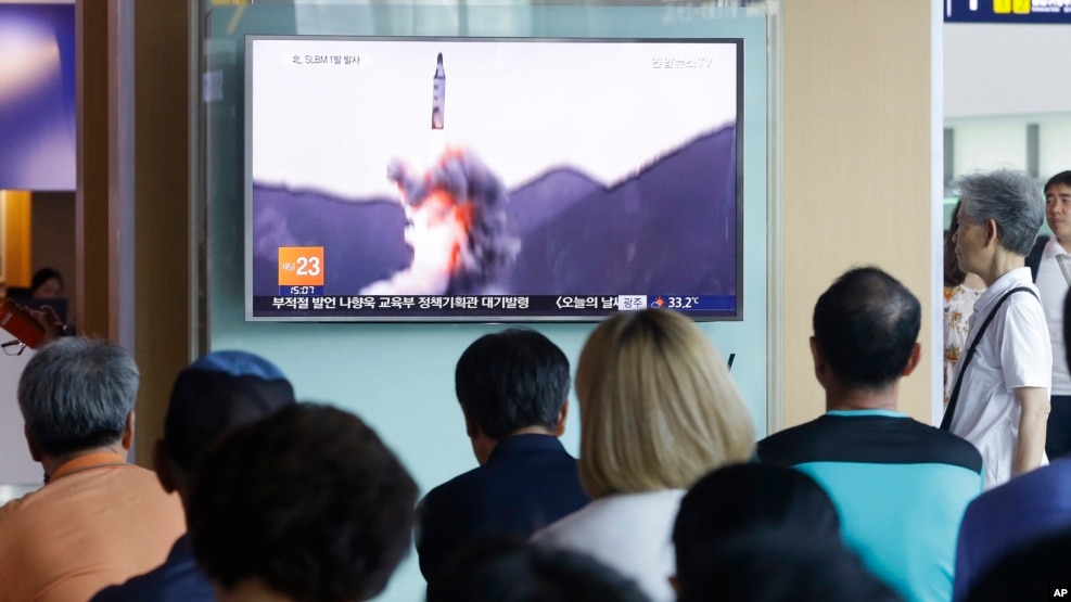 La surcoreanos ven un programa de noticias mostrando imágenes viejas del lanzamiento de un misil balístico norcoreano.