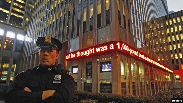 Un policía de Nueva York monta guardia frente a una pantalla que menciona el arresto de un sospechoso de Bangladesh que pensaba atentar en la ciudad, contra la Reserva Federal.
