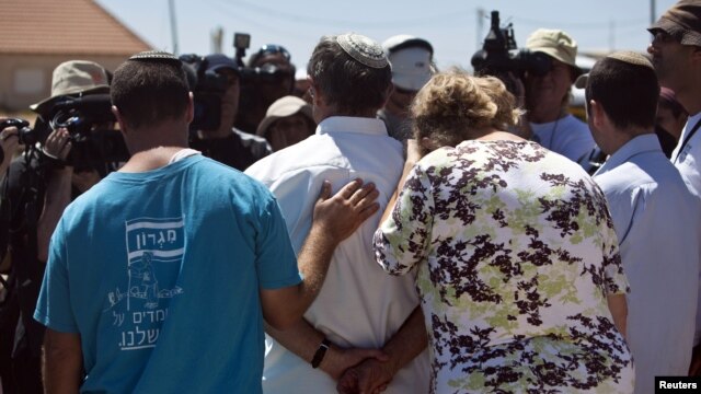 Jewish settlers speak to the media after leaving their homes in the West Bank outpost of Migron September 2, 2012.