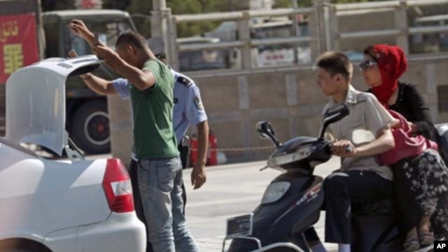 A police office checks the trunk of a car of an ethnic Uighur man as security forces are deployed at a square in Kashgar in China's western Xinjiang region, August 2, 2011.
