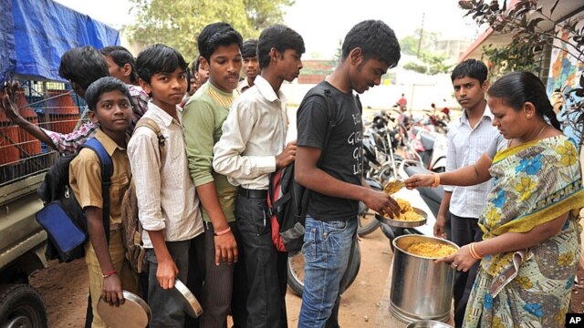 An Indian teacher serves the mid-day meal to children at a Government High School in Hyderabad, January 10, 2012. 