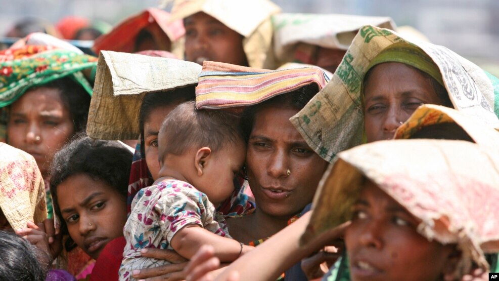 Ảnh tư liệu - Một phụ nữ Bangladesh che nắng cho con khi xếp hàng tại cửa hàng gạo ở Dhaka, ngày 5 tháng 4 năm 2008.