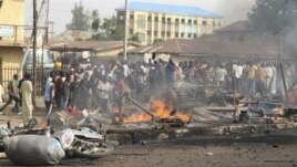 Mutane sun taru a wani wurin da bam ya tashi kan wata hanya a Kaduna, arewacin Najeriya ran 8 Afrilu, 2012.