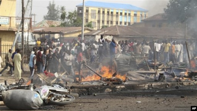 Mutane sun taru a wani wurin da bam ya tashi kan wata hanya a Kaduna, arewacin Najeriya ran 8 Afrilu, 2012.
