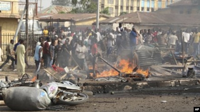 People gather at the site of a bomb explosion at a road in Kaduna, Nigeria on Sunday, April 8, 2012.