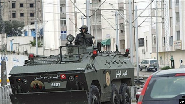 A soldier drives an armored vehicle through Ettadhamoun, west of Tunis, where riots reportedly took place, Jan 12, 2011