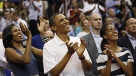 U.S. President Barack Obama, first lady Michelle Obama and daughter Malia (R) applaud as they look up at the video screen as they attend the Olympic men's exhibition basketball game between Team USA and Brazil in Washington July 16, 2012.