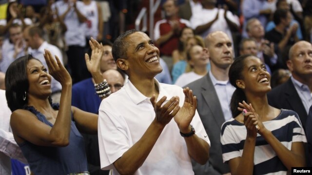 U.S. President Barack Obama, first lady Michelle Obama and daughter Malia (R) applaud as they look up at the video screen as they attend the Olympic men's exhibition basketball game between Team USA and Brazil in Washington July 16, 2012.