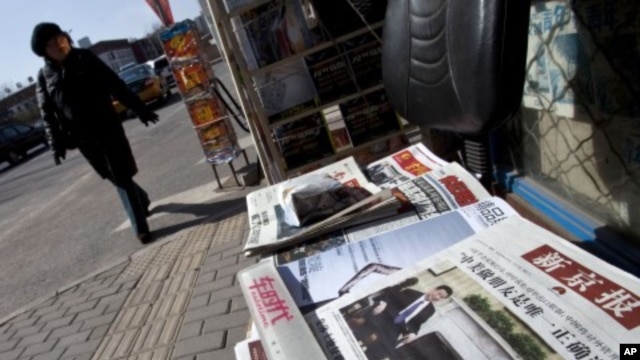 A woman walks past a Beijing newsstand where a newspaper front page shows a photo of Chinese Vice President Xi Jinping and U.S. President Barack Obama, February 16, 2012.