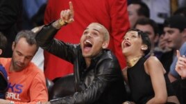 Chris Brown ríe durante el juego de baloncesto de la NBA, donde apareció de nuevo con su pareja, Rihanna.