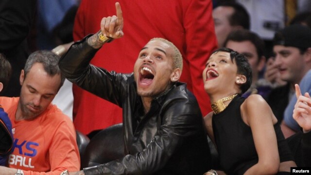 Chris Brown ríe durante el juego de baloncesto de la NBA, donde apareció de nuevo con su pareja, Rihanna.