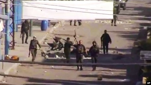 In this image from TV shown on the internet made available by the Sham News Network December 20, 2011, soldiers walk down the street in Daraa, Syria.