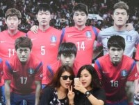 Two women take a selfie with a poster of the Korean national football team.