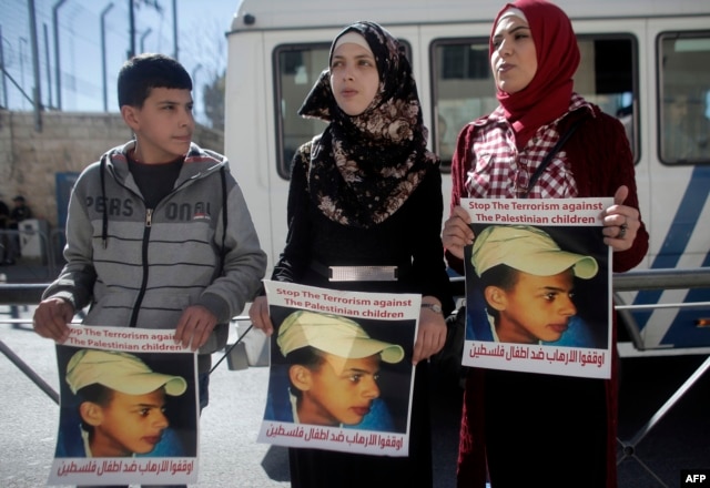 Relatives of Palestinian teenager Mohammed Abu Khdeir who was killed in 2014, hold posters bearing his portrait outside the Jerusalem district court during a hearing on Feb. 4, 2016.