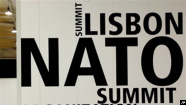 A man walks by a logo printed on a wall inside the NATO summit venue in Lisbon, Portugal on Thursday, Nov. 18, 2010. Heads of State of NATO member countries gather for a two day summit beginning on Friday, and will discuss such topics as Afghanistan and m