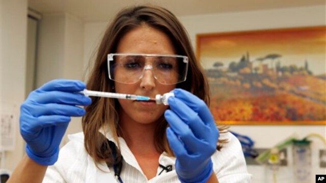 Dr Felicity Hartnell, who is a clinical research fellow at Oxford University, holds a vial of an experimental vaccine against Ebola in Oxford, England  Wednesday Sept. 17, 2014. A former nurse will be the first of 60 healthy volunteers in the UK who will receive the vaccine. The vaccine was developed by the U.S. National Institutes of Health and GlaxoSmithKline and targets the Zaire strain of Ebola, the cause of the ongoing outbreak in West Africa. A trial of the same vaccine has already begun in the U.S.  (AP Photo/Steve Parsons/Pool)