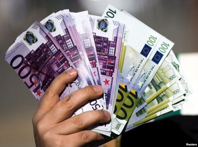 An activist shows fake banknotes during a demonstration outside the European Commission (EC) headquarters ahead of statements by the EC on the effectiveness of existing measures against tax evasion and money-laundering in light of the recent Panama Paper revelations, in Brussels, Belgium, April 12, 2016.