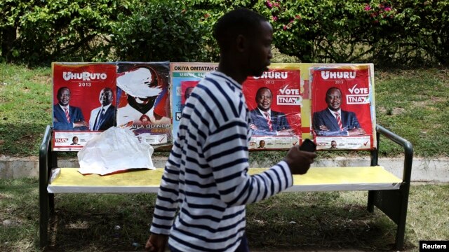A man passes by posters of presidential candidates Uhuru Kenyatta and Prime Minister Raila Odinga in Nairobi, March 8, 2013. 