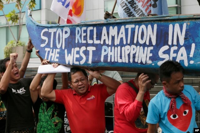 Protesters carry a boat painted with slogans during a rally outside the Chinese Consulate in Makati city, east of Manila, Philippines, to protest China's reclamations of disputed islands off South China Sea, July 3, 2015.