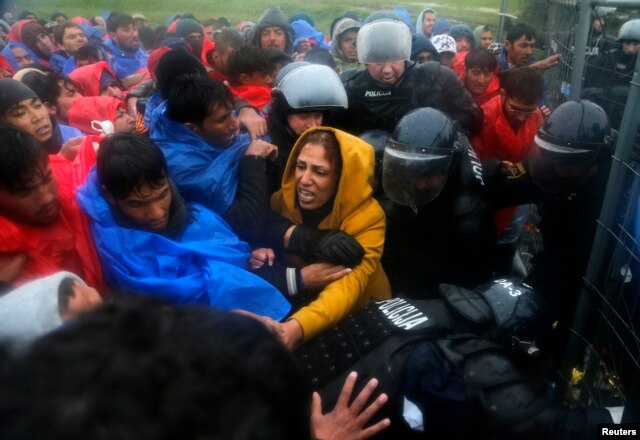 Slovenian policemen keep order as migrants attempt to board the first bus after opening the border with Slovenia in Trnovec, Croatia, Oct. 19, 2015.