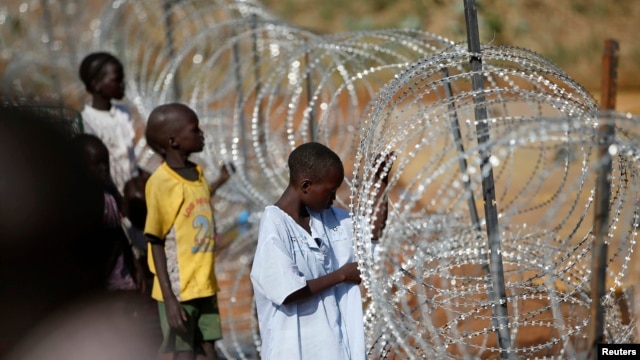 Internally displaced boys stand next to barbed wire inside a United Nations Missions in Sudan (UNMIS) compound in Juba December 19, 2013. 