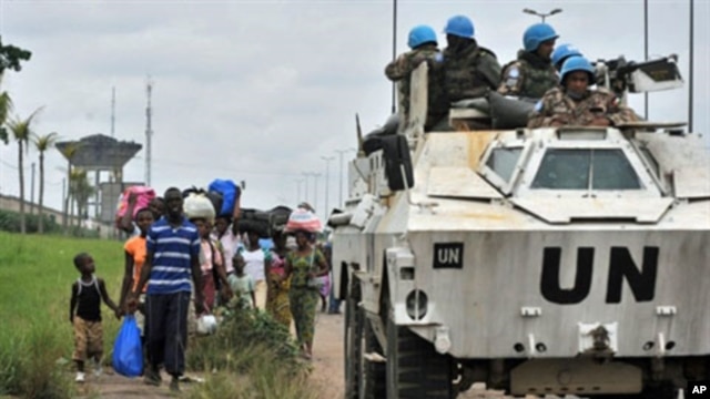 Inhabitants of the Abobo district in Abidjan flee the area past a United Nations armored vehicle following fresh clashes between forces loyal to rival claimants for the presidency on February 27, 2011