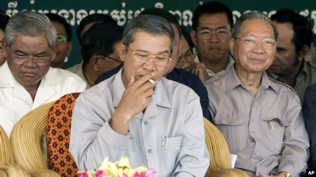 Cambodia's Prime Minister Hun Sen, center, smokes as he sits with Interior Minister Sar Kheng, left, and Finance Minister Keat Chhun, right, during the inauguration of the China-funded construction of a bridge in Mouk Kampoul district, Kandal province, some 20 kilometers (12 miles) north of Phnom Pen, Cambodia, file photo. 