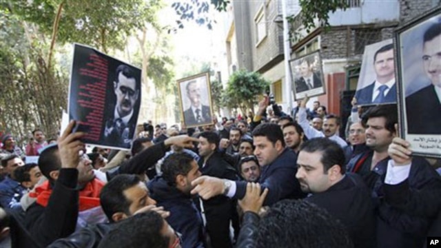 Carrying pictures of Syrian President Bashar Assad, a group of Syrians, some supporters of Assad, right, and some opposed to his regime, left, stage a protest outside the Syrian embassy in Cairo, Egypt, March 15, 2011