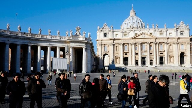 People walk in St. Peter's Square at the Vatican, February 19, 2013. 