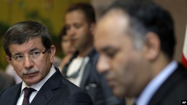Turkish Foreign Minister Ahmet Davutoglu, left, speaks to Vice-Chairman of the Executive Board of the Libyan National Transitional Congress Ali al-Issawi, right, during a news conference after their meeting in the rebel-held Benghazi, Libya, Sunday, July 