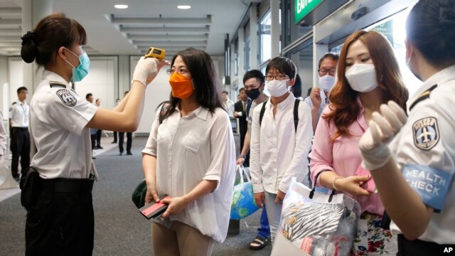Como medida de precaución pasajeros que llegan al aeropuerto de Hong Kong son revisados por las autoridades sanitarias.