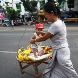 A street vendor carries her son and bananas on a street in Rangoon.