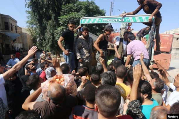 People gather to buy fresh produce that was brought into rebel held areas of Aleppo by private traders from a newly opened corridor that linked besieged opposition held eastern Aleppo with western Syria that was captured recently by rebels, in Aleppo, Aug. 11, 2016.