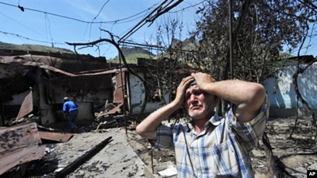 An ethnic Uzbek holds his head in his hands as he stands beside the wreckage of his burned out home in Osh (file photo – 14 June 2010)