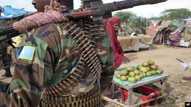 A fruit seller looks across as a Somali government soldier stands guard in Afgoye, west of the capital Mogadishu, in Somalia on June 7. A recent survey reveals widespread agreement on many key provisions of the draft constitution.