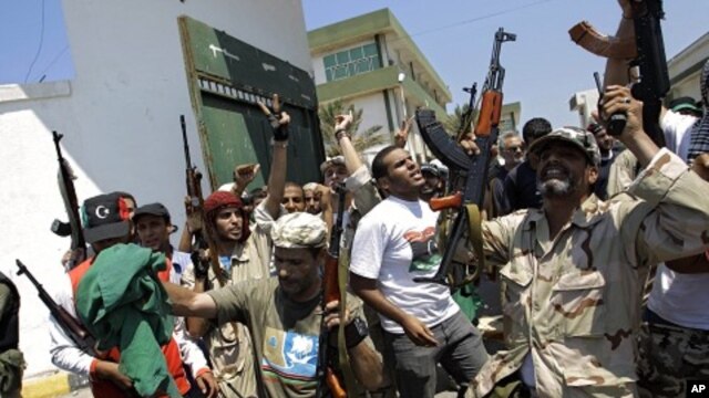 Libyan rebel fighters gesture at the former female military base in Tripoli, LIbya, August 22, 2011