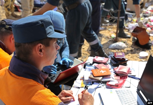 Russian rescuer checking passports collected from the wreckage of a A321 Russian airliner in Wadi al-Zolomat, a mountainous area of Egypt's Sinai Peninsula. (Russian Emergency Ministry Handout photo)