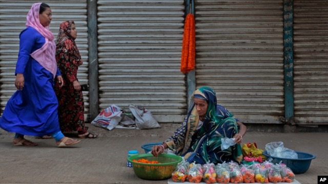 Two Bangladeshi Muslim women walk past a Hindu woman selling flowers by a roadside in Dhaka, Bangladesh, March 28, 2016. Hindus, along with Buddhists, represent the main minority groups in the majority Muslim country.