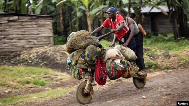 People ride with their belongings on a wooden bicycle as they flee from renewed fighting between Congolese army and M23 rebels near the eastern Congolese city of Goma, July 24, 2012. 