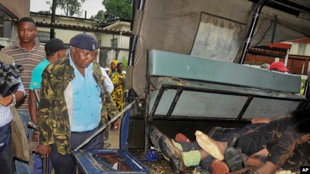 Afisa wa polisi akiwa na bunduki analinda miili ya watu sita walouliwa waliposhambulia kambi ya jeshi Mombasa, Kenya Jumapili Nov 2, 2014 