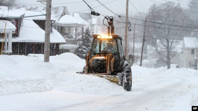 Una pala mecánica remueve la nieve en Marlborough, Massachusetts donde se espera entre 30 y 60 centímetros más de nieve.
