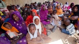Women and children wait to participate in a vaccination campaign against meningitis at the community center in Al Neem camp for Internally Displaced People in El Daein, East Darfur, Sudan, October 8, 2012.